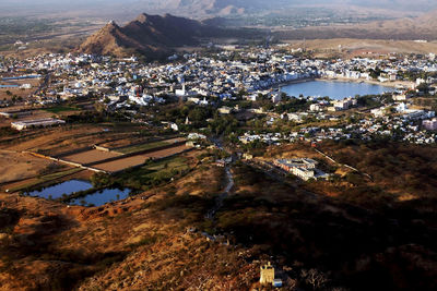 Aerial view of lake amidst houses in pushkar by mountain