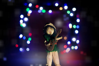 Close-up of figurine against illuminated lights at night