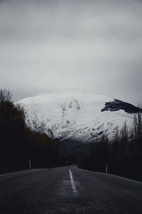 Road by snowcapped mountain against sky