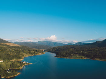 Scenic view of lake and mountains against blue sky