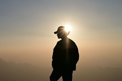 Silhouette woman standing against sky during sunset