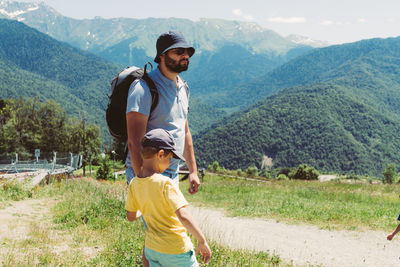 Millenial bearded tourist man hiking in mountains with child. father and son spend time together