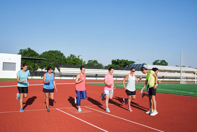 Group of women practice pre-workout stretching with their young traine