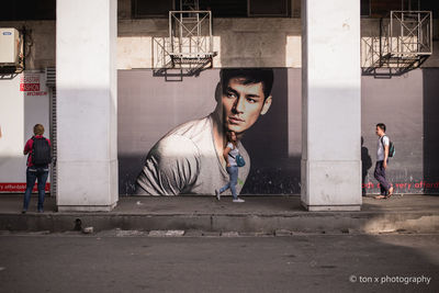 Portrait of young couple sitting on street in city