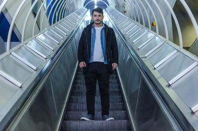 Full length portrait of confident man standing on escalator
