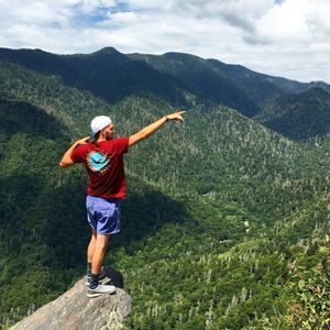 Rear view of male hiker standing on rock against landscape