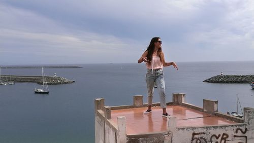 Smiling young woman standing at observation point by sea