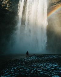 Rear view of person looking at waterfall