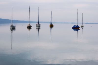 Sailboats moored on sea against sky