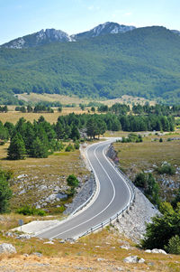 Scenic view of road by mountains against sky