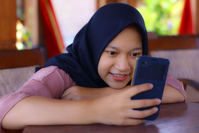 Portrait of smiling girl using mobile phone at home