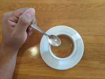 Cropped image of hand holding coffee cup on table