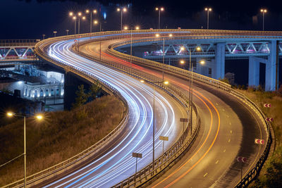 Highway at night lights. fast car light path, trails and streaks on interchange bridge road. night