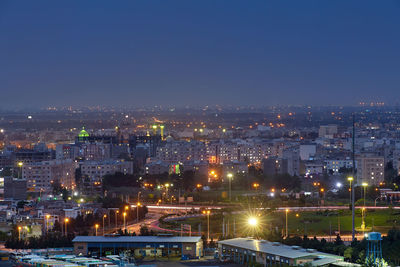 Illuminated buildings in city against clear sky at night