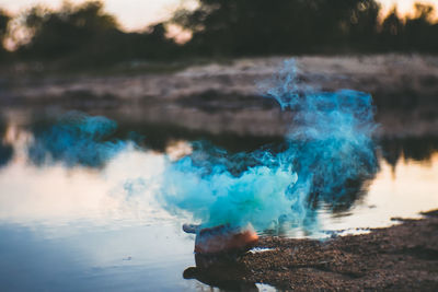 Flower pot emitting smoke by lake during sunset