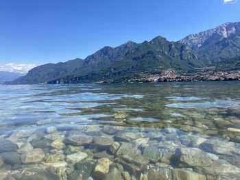 Scenic view of sea and mountains against blue sky