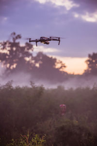 Low angle view of helicopter flying against sky during sunset