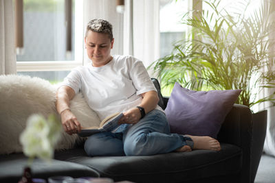 A woman is sitting on the couch reading a book