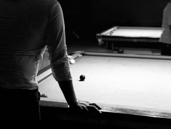 Midsection of man standing by pool table