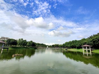 Scenic view of lake by trees and building against sky