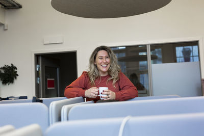 Smiling woman holding mug in office