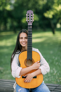 Portrait of a young girl guitarist who smiles and holds a guitar in her hands. girl-musician, music