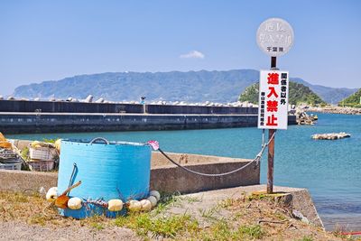 Information sign by sea against clear sky