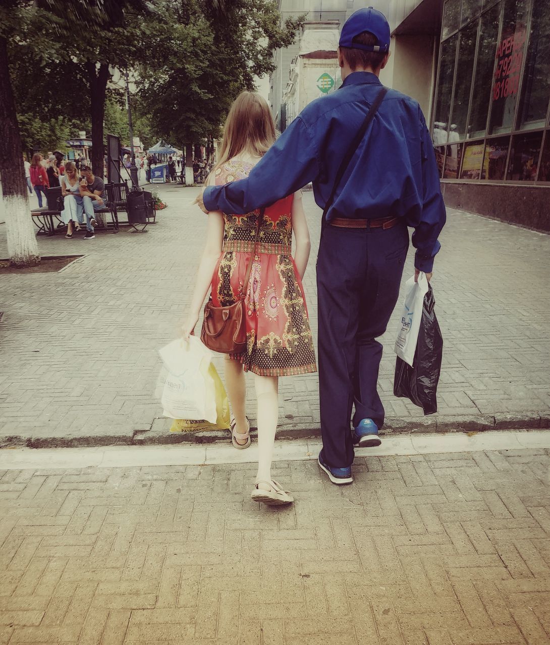 REAR VIEW OF MAN AND WOMAN WALKING ON STREET