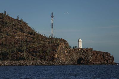 Lighthouse by sea against sky