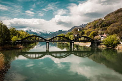 Arch bridge over lake against sky