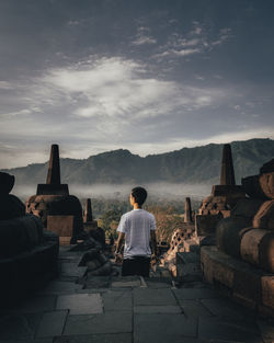 Rear view of man standing at temple against sky