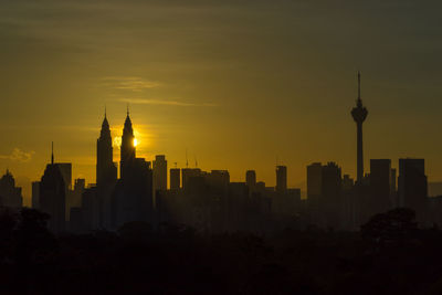 Silhouette of buildings in city during sunrise