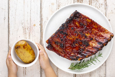 Roasted barbecue pork spare ribs with honey, oregano and rosemary in ceramic plate and baked potato