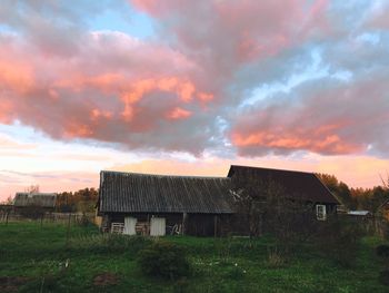 Houses on field against sky during sunset