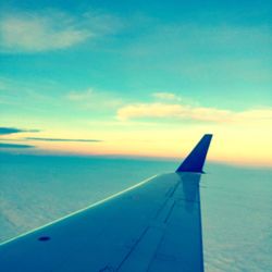 Airplane wing over sea against sky during sunset