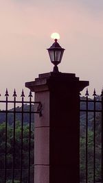 Illuminated street light against sky at dusk