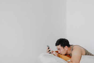 Portrait of young woman sitting on white background