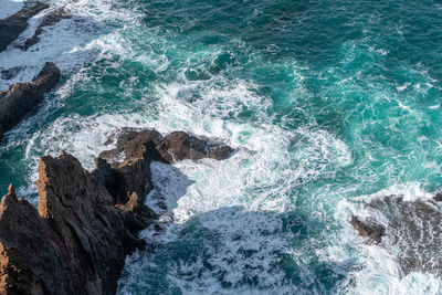 High angle view of waves splashing on rocks