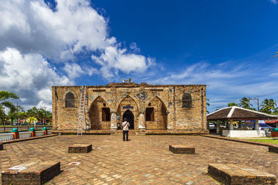 People standing outside historic building against sky