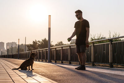 Young man is playing with his dog on empty street in the morning.