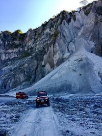 Cars on road by mountain against sky