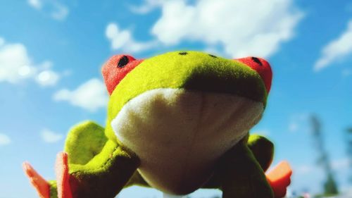 Close-up of hand holding fruit against blue sky