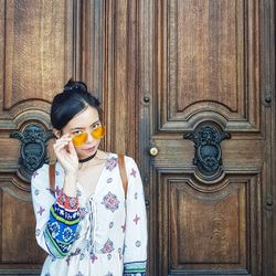 Portrait of woman standing against door