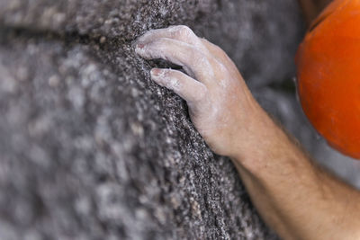 Close up of finger with chalk in tiny crack and helmet while climbing