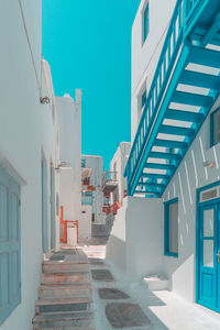 Low angle view of staircase amidst buildings against clear blue sky