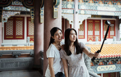 Portrait of smiling young woman against built structure