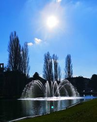 Fountain by lake against sky