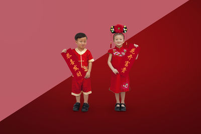 Portrait of boy standing against red background