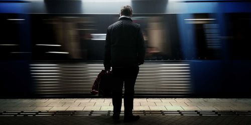 Rear view of man walking on railroad station platform