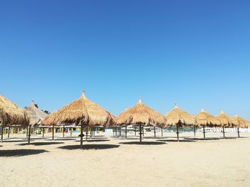 Panoramic view of beach umbrellas against clear blue sky